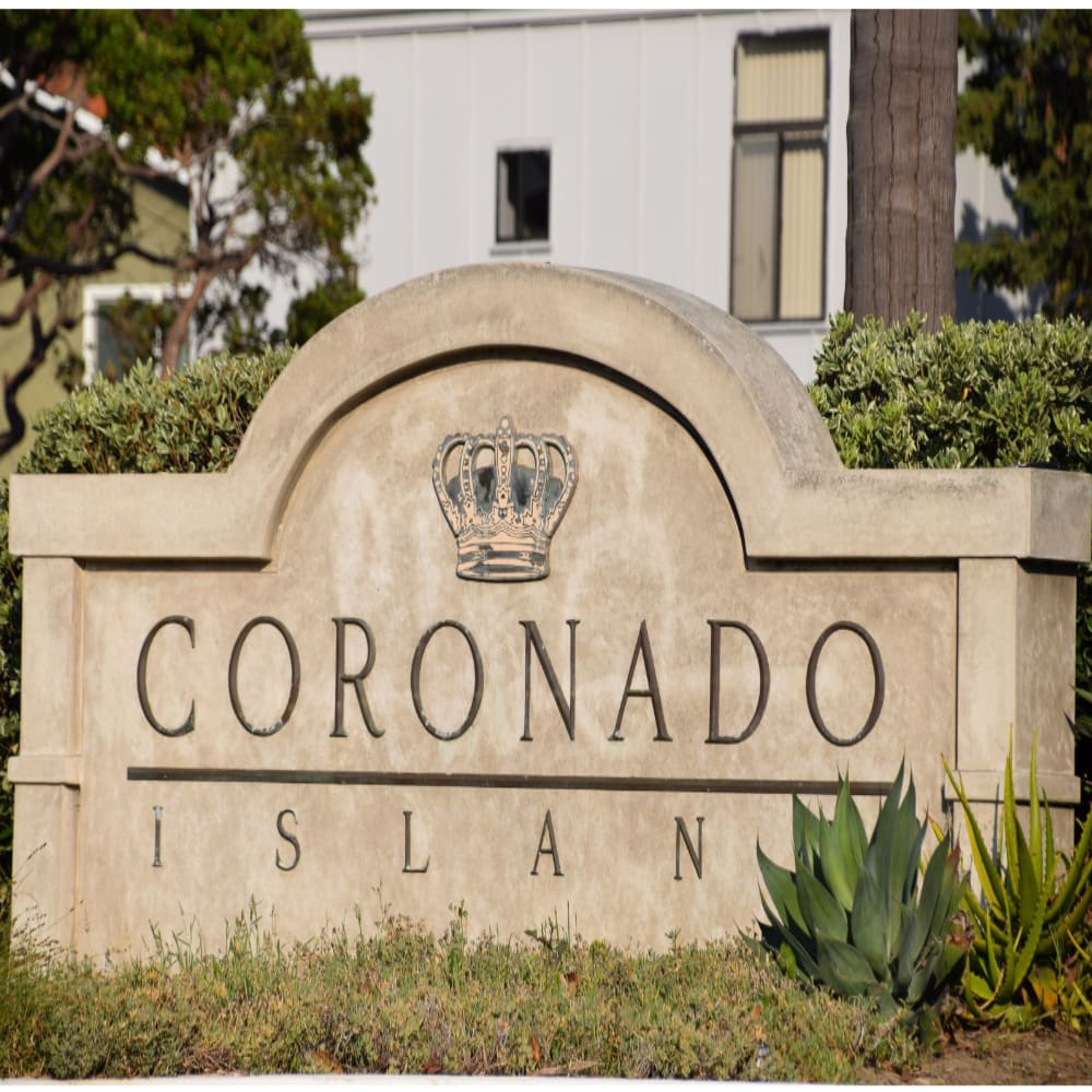Cleaner carefully wiping kitchen counters and polishing fixtures in occupied Coronado coastal home