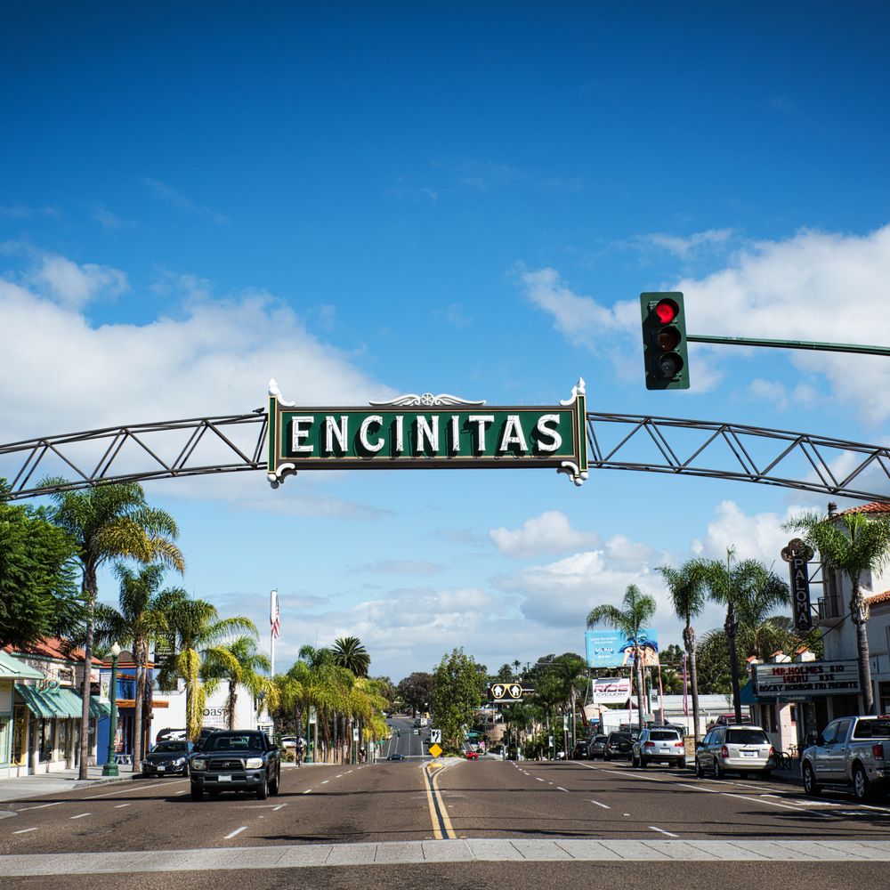 Cleaner wiping kitchen counters and cabinet fronts in bright Encinitas family home